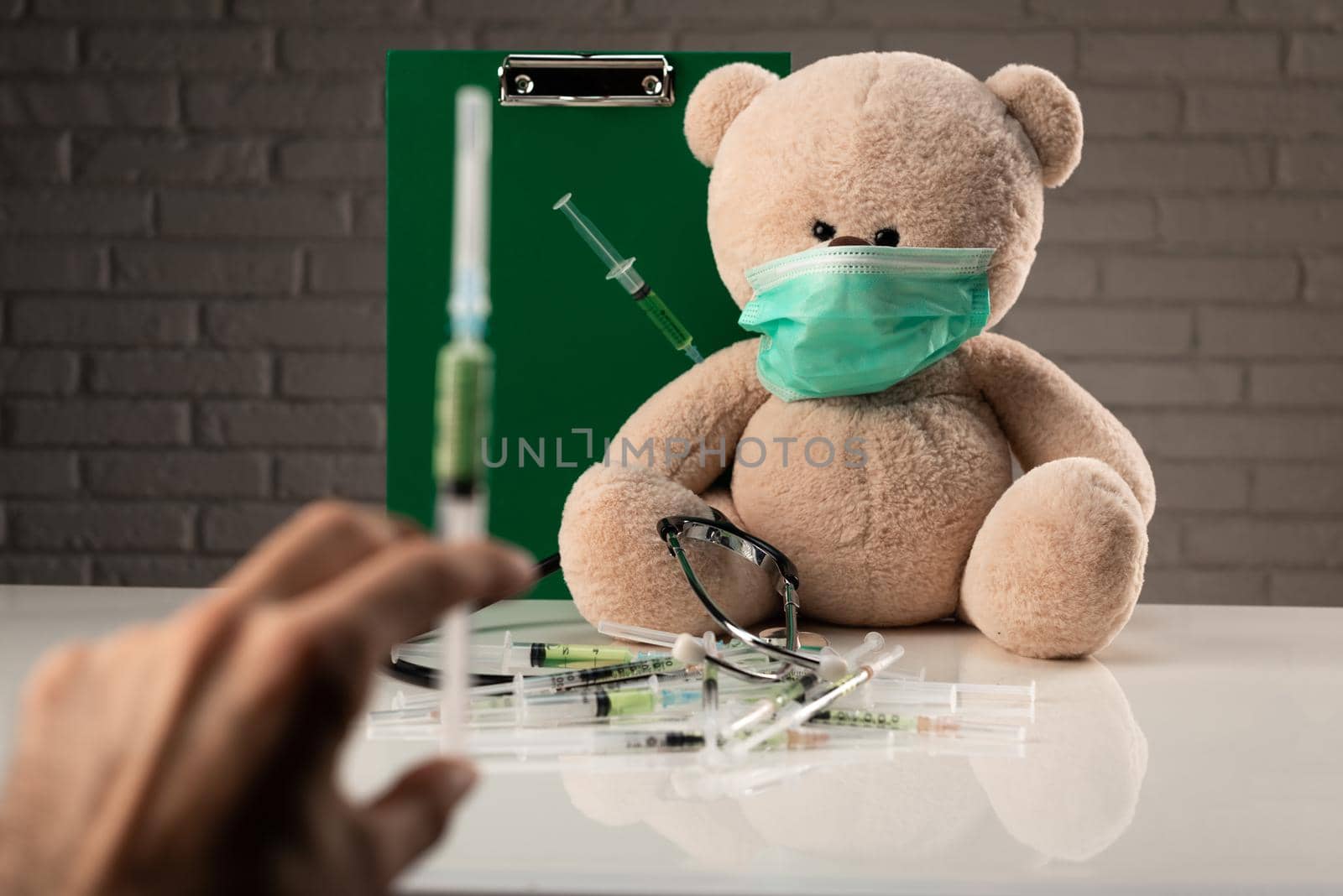 a teddy bear in a medical mask with syringes in his shoulder , on the doctor 's desk by Rotozey