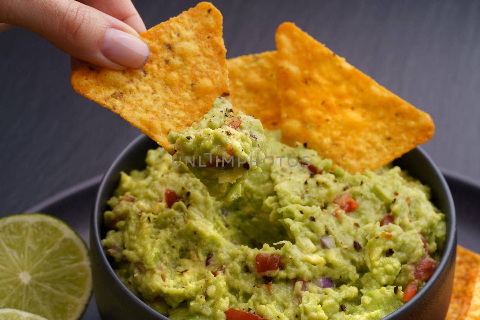 Guacamole and chips or nachos in black plate on a black background. High quality photo