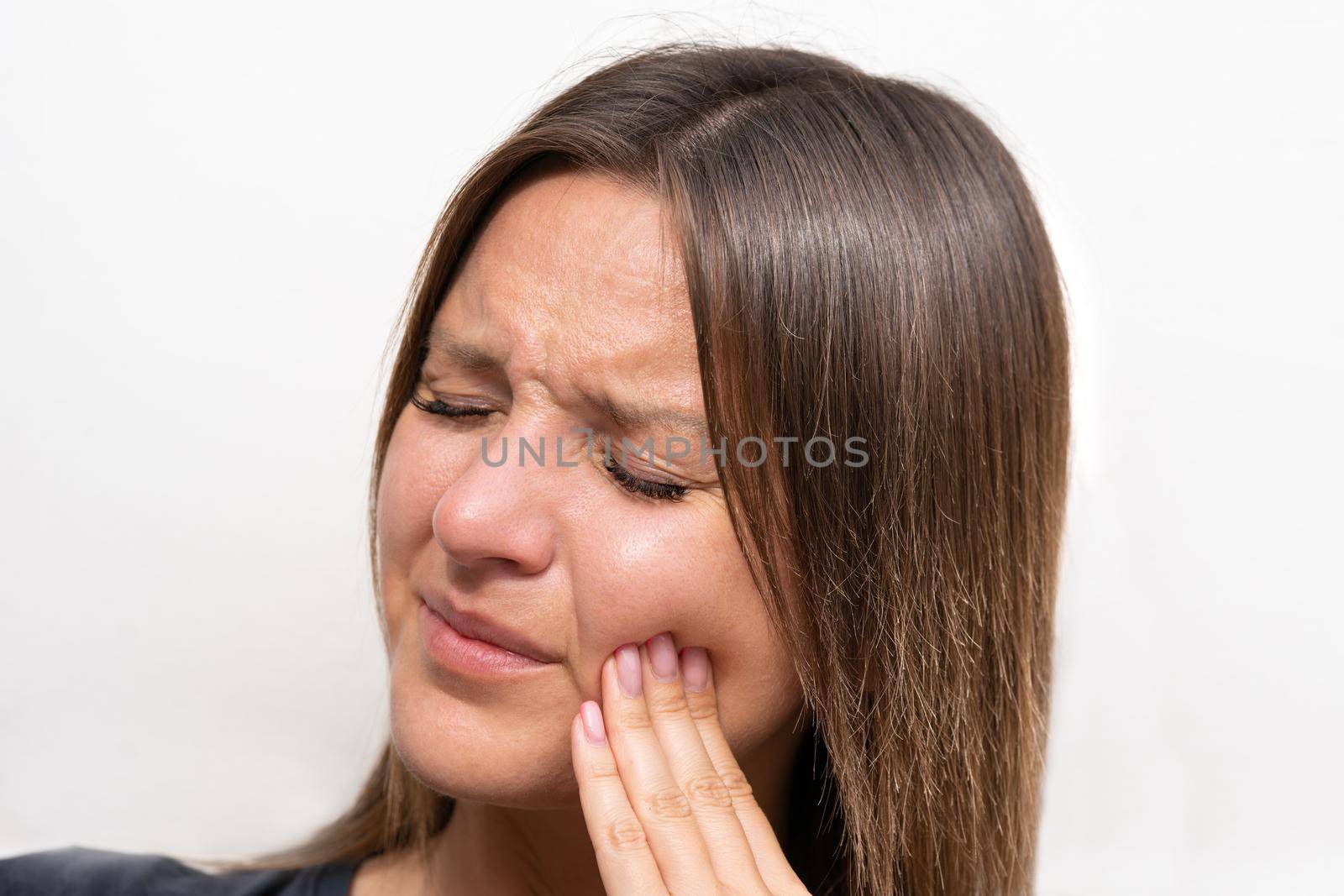 Young woman touching her cheek because of strong tooth pain. Female suffering from toothache. Woman face with painful expression. Teeth problem. High quality photo