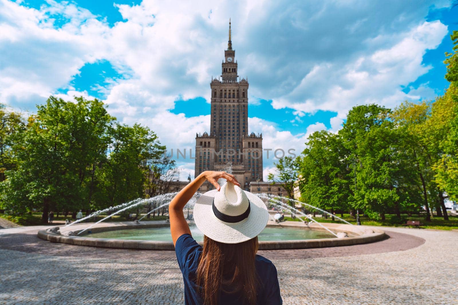 Young tourist woman in white sun hat walking in the park in Warsaw city, Poland. Summer vacation in Warsaw by DariaKulkova