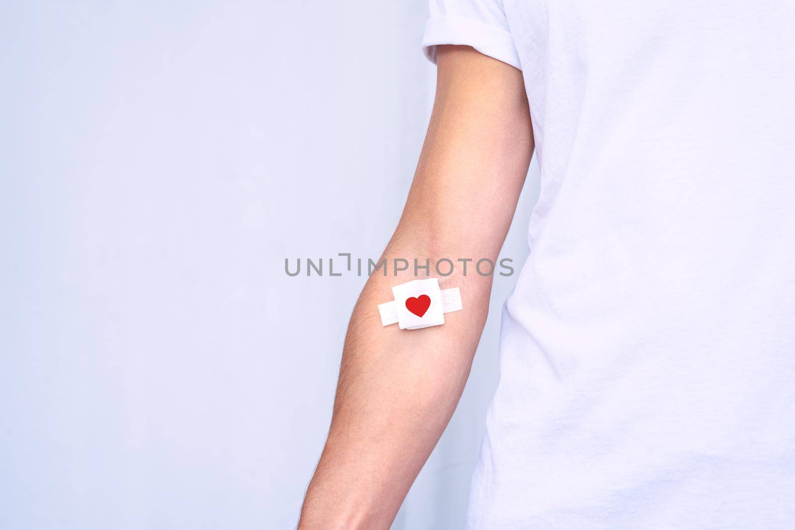 Blood donation. Blood donor with bandage after giving blood on a white background. Copy space by DariaKulkova