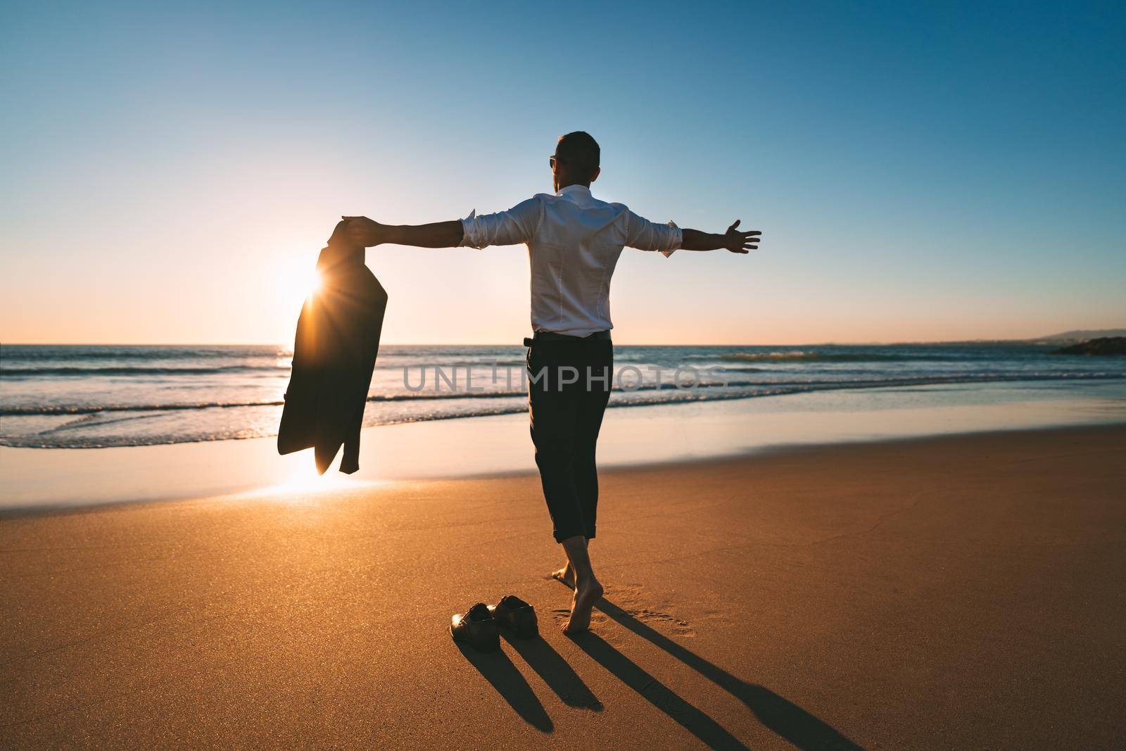 Life is good. Man with open arms enjoying life and freedom on the beach with sunset. High quality photo