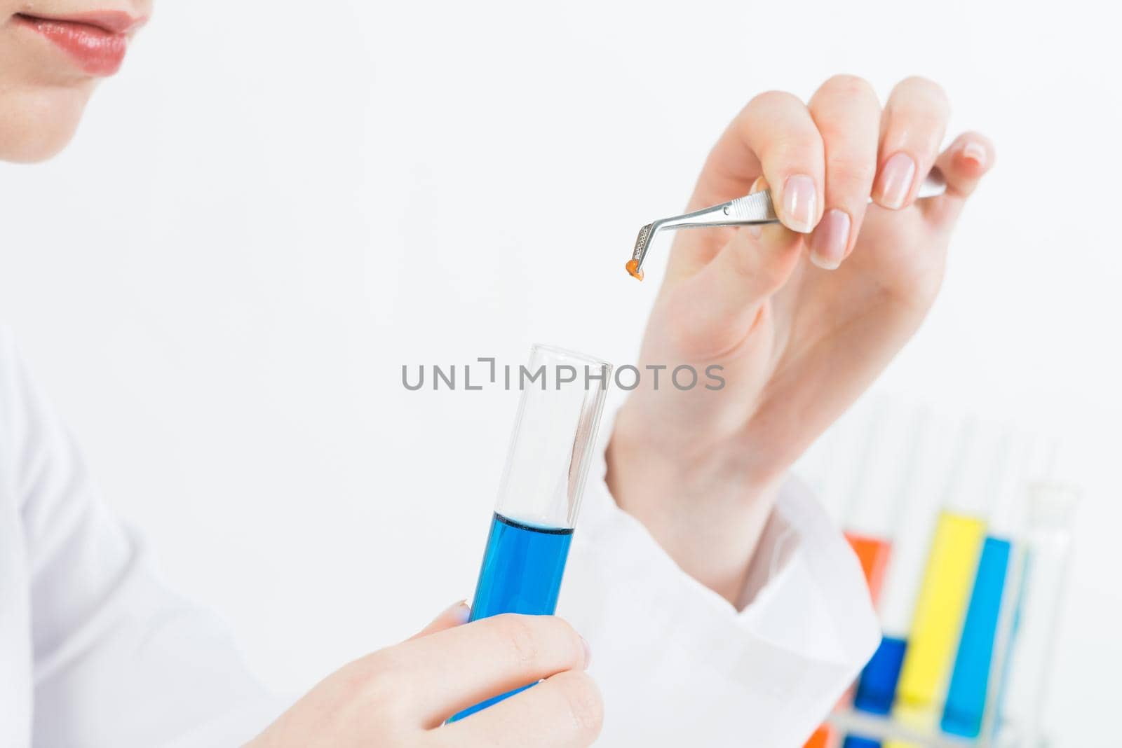 Scientist puts sample into test tube with liquid. Biochemistry laboratory analysis and experimentation. Closeup woman hands holding test tube and tweezers. Biology researching and lab testing.