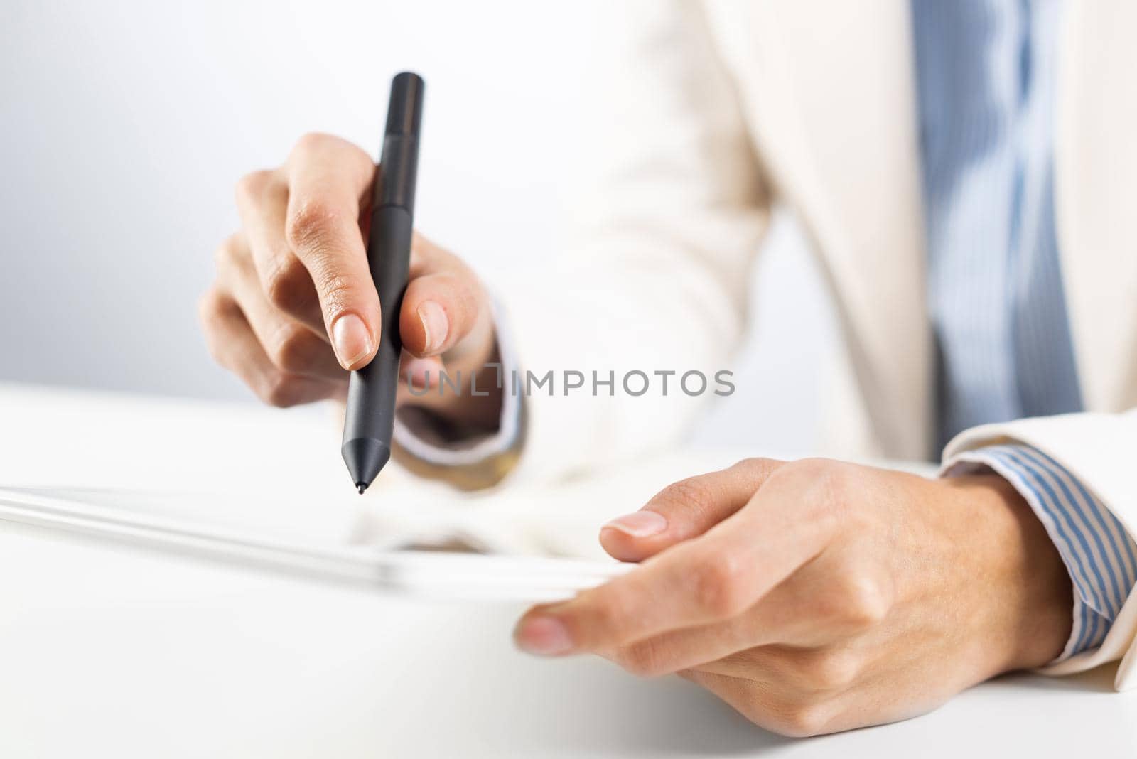 Man in business suit using tablet computer. Close-up of male hands holding pen and tablet gadget. Businessman at workplace in office. Mobile smart device in business occupation. Digital technology