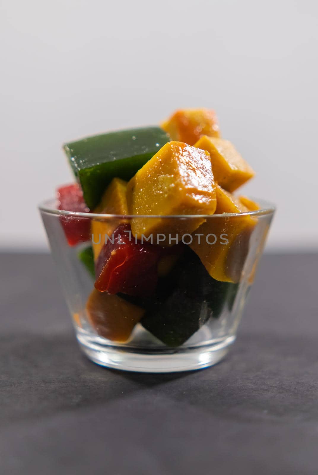 Glass of colorful Mexican fruit paste slices on black surface by Kanelbulle