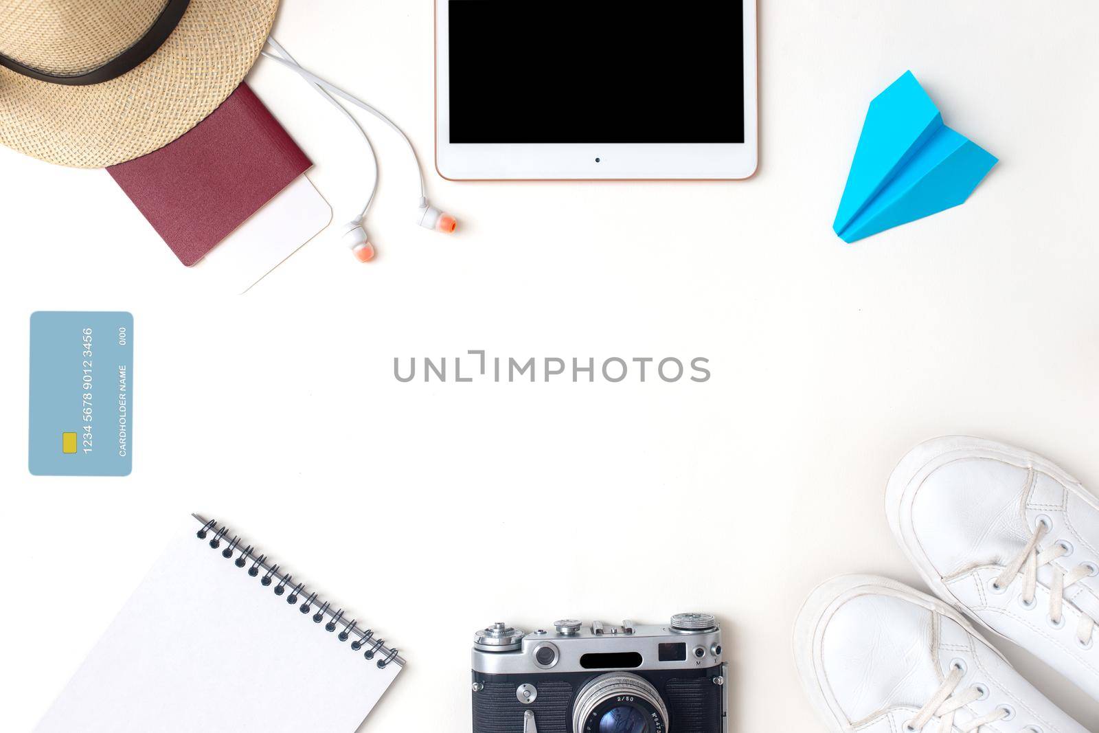Summer travel accessories set top view on white background : passport, camera, straw hat, digital tablet, white sneakers , headphones, credit card, paper airplane . Copy space.