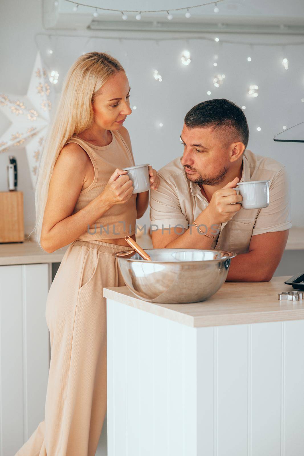 Caucasian couple drinking hot chocolate while preparing dough for gingerbread. by XGroup