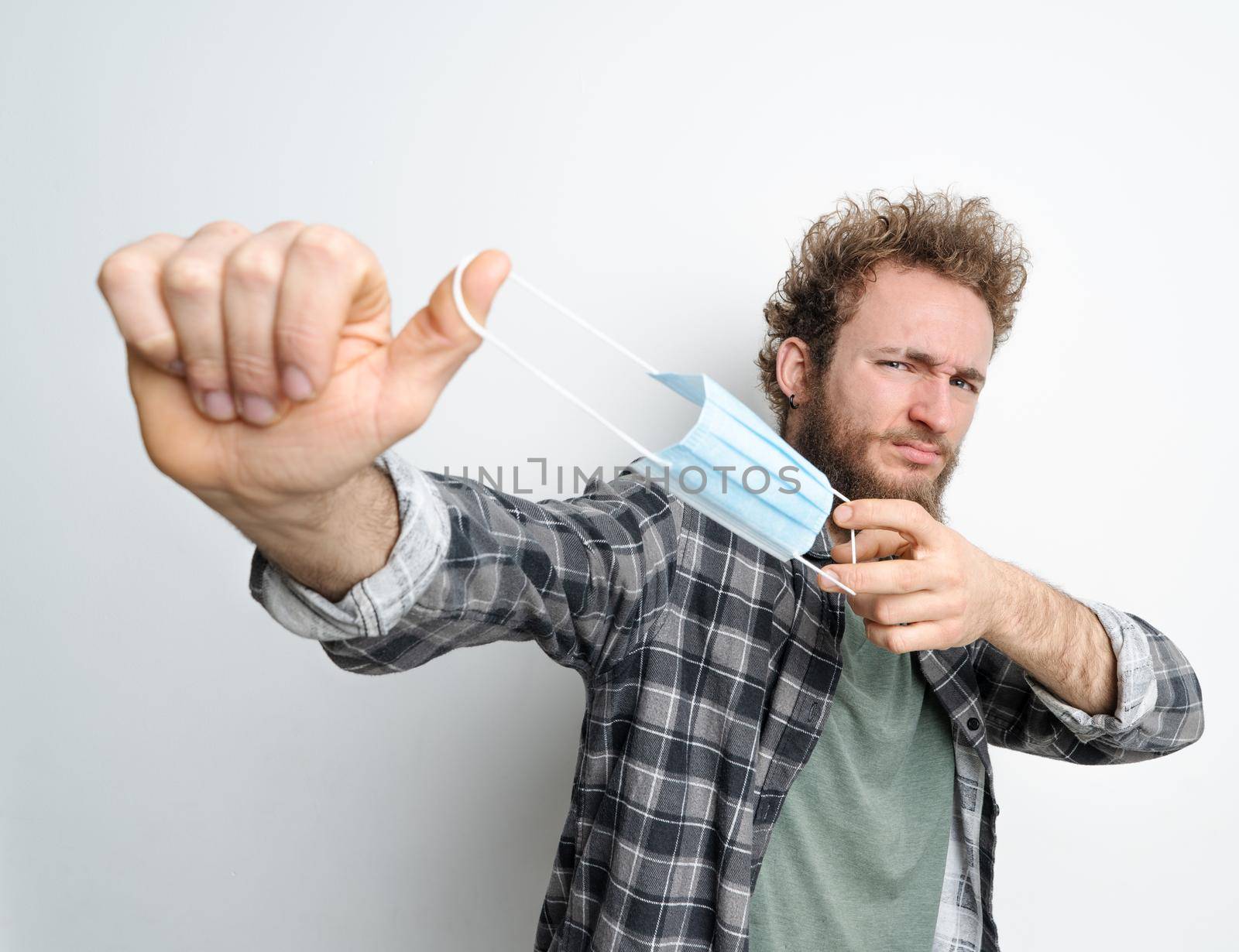 Guy Took off his Mask in Gisgust and is Ready to Flick the Mask and Throw it Away. End of Quarantine, Cancellation of Mask Mode, Covid-19, Close-up. White Background. High quality photo