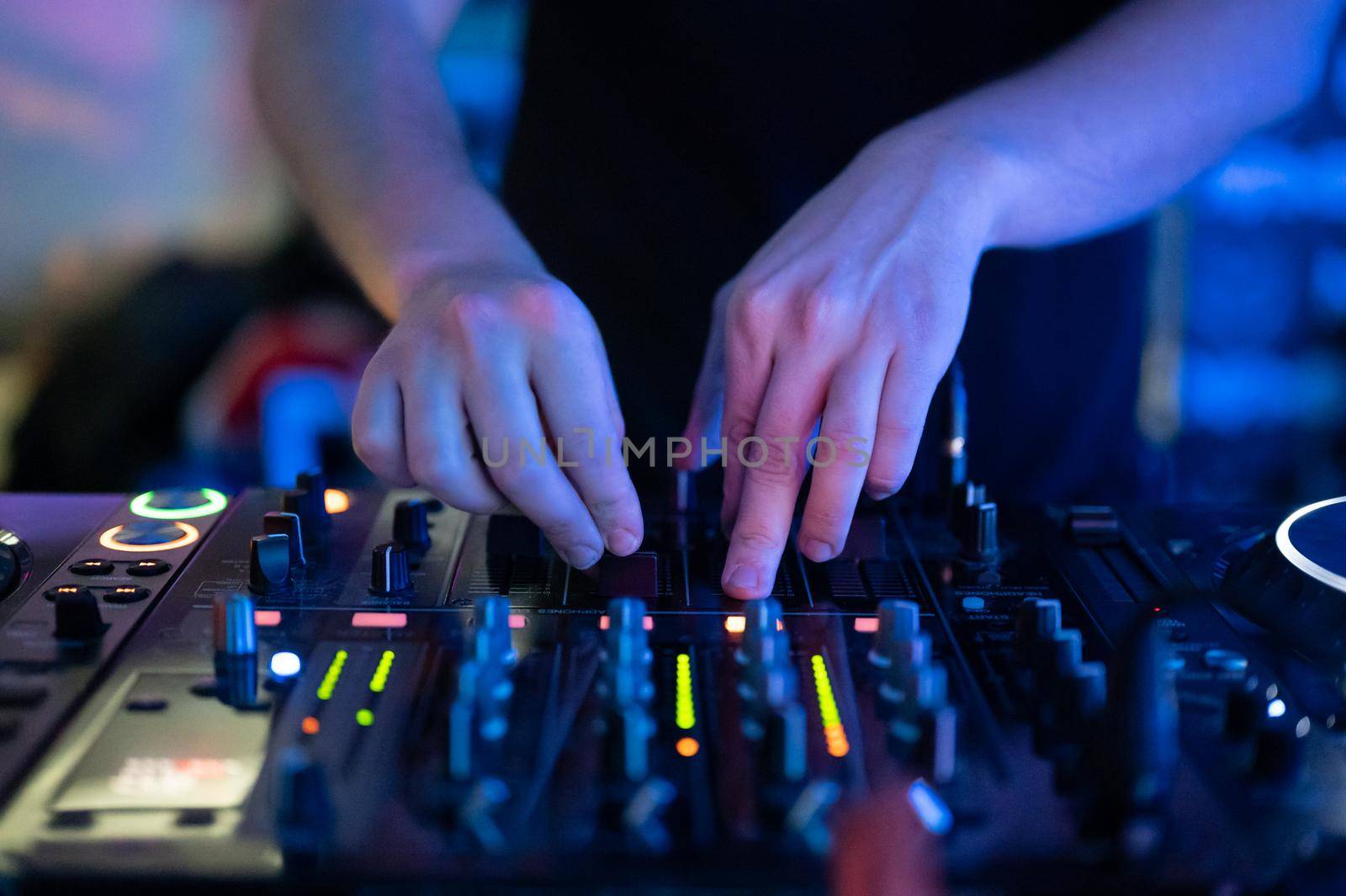 Close up Front view of of DJ hands controlling a music table in a night club. by HERRAEZ