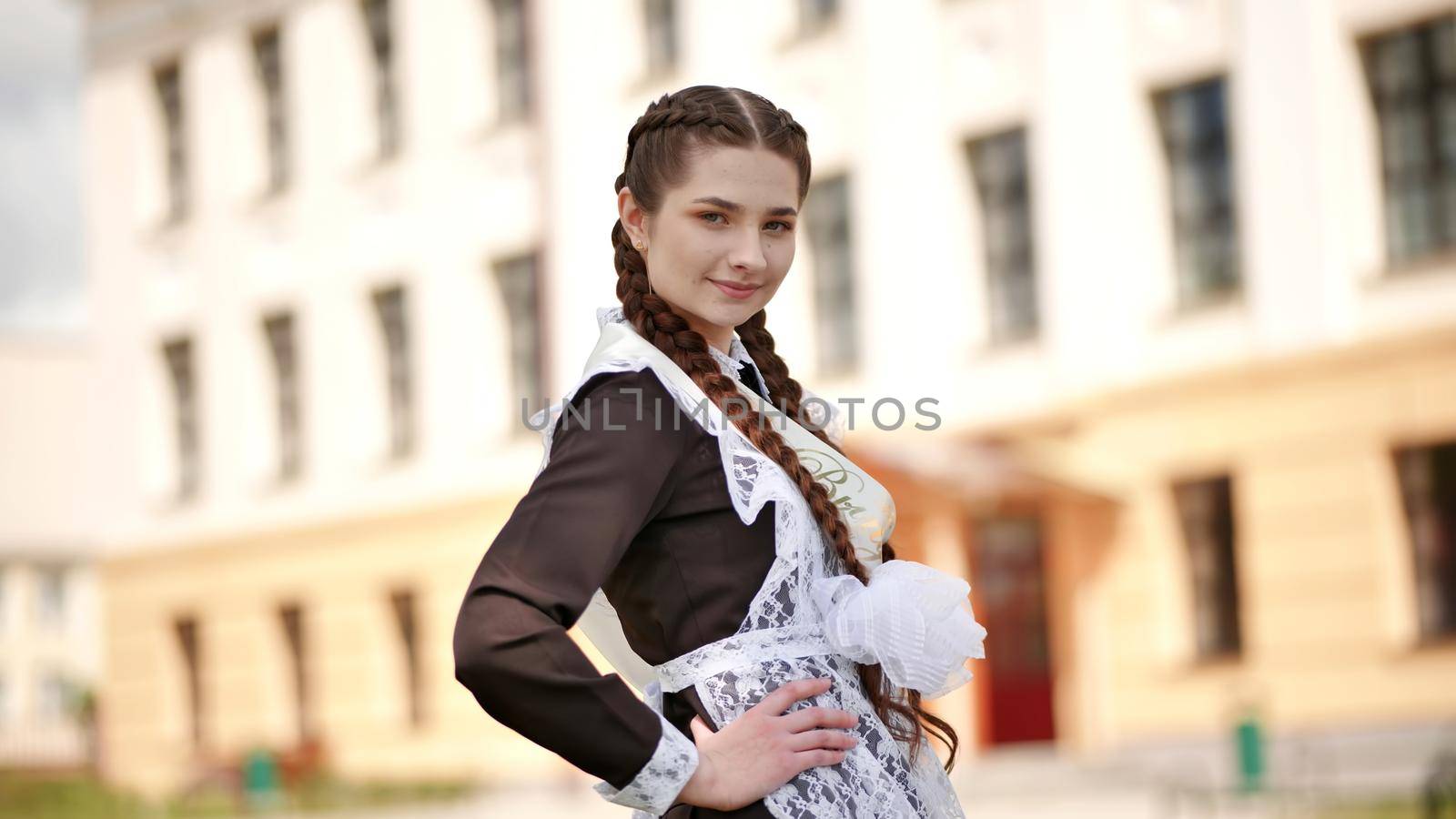 Happy Russian graduate with pigtails posing on graduation day