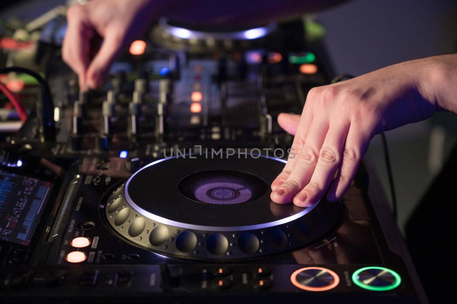 Close-Up of Dj Mixer Controller Desk in Night Club Disco Party. DJ Hands touching Buttons and Sliders Playing Electronic Music . High quality photography.
