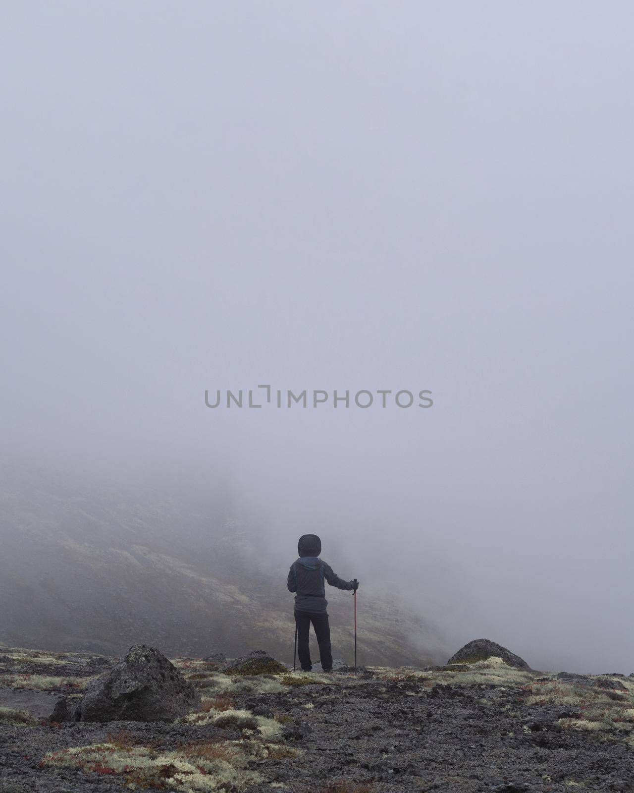 Woman hiker stands on the edge of a cliff in the clouds. new unknown path