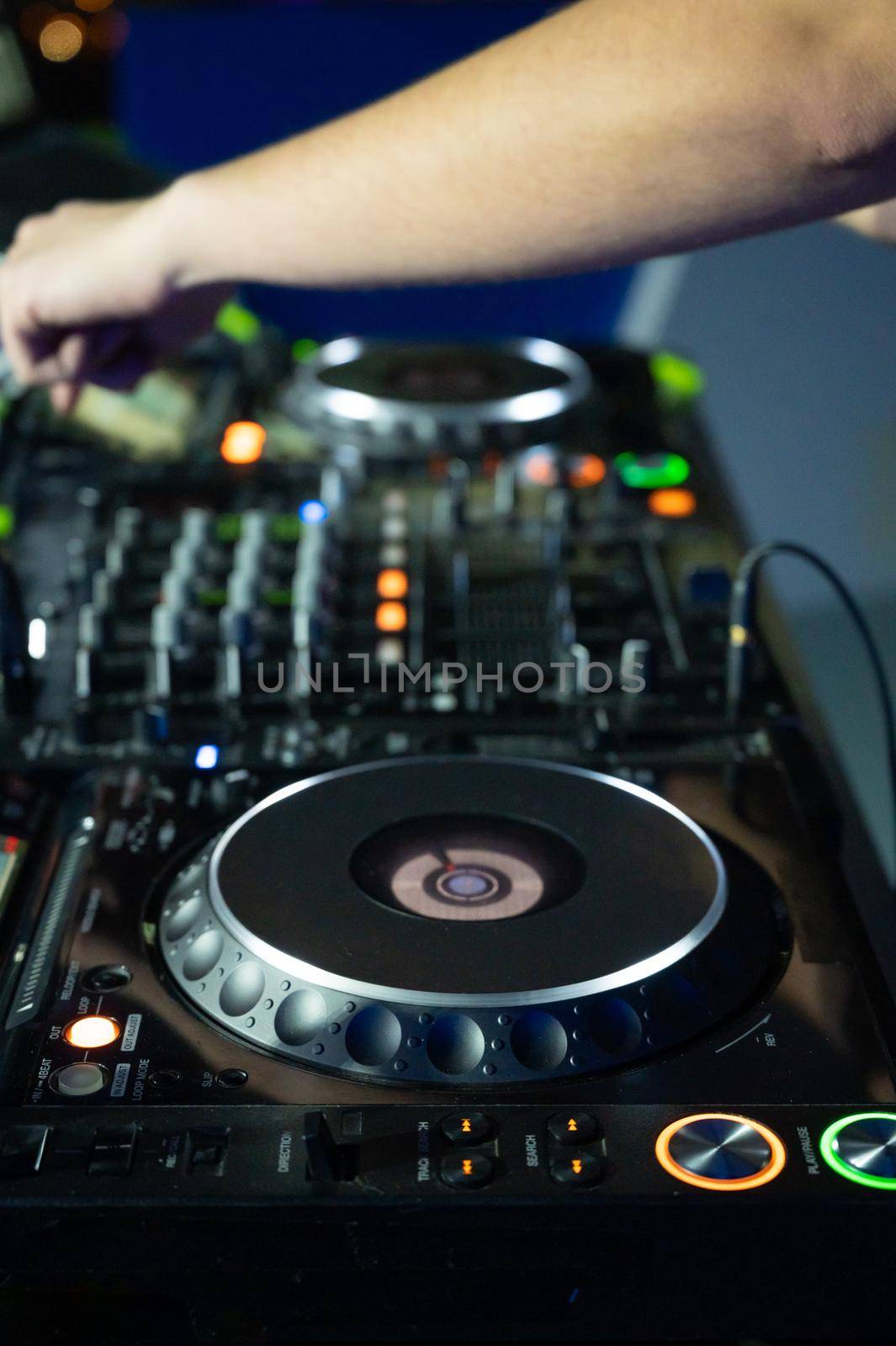 Close-Up of Dj Mixer Controller Desk in Night Club Disco Party. DJ Hands touching Buttons and Sliders Playing Electronic Music . High quality photography.