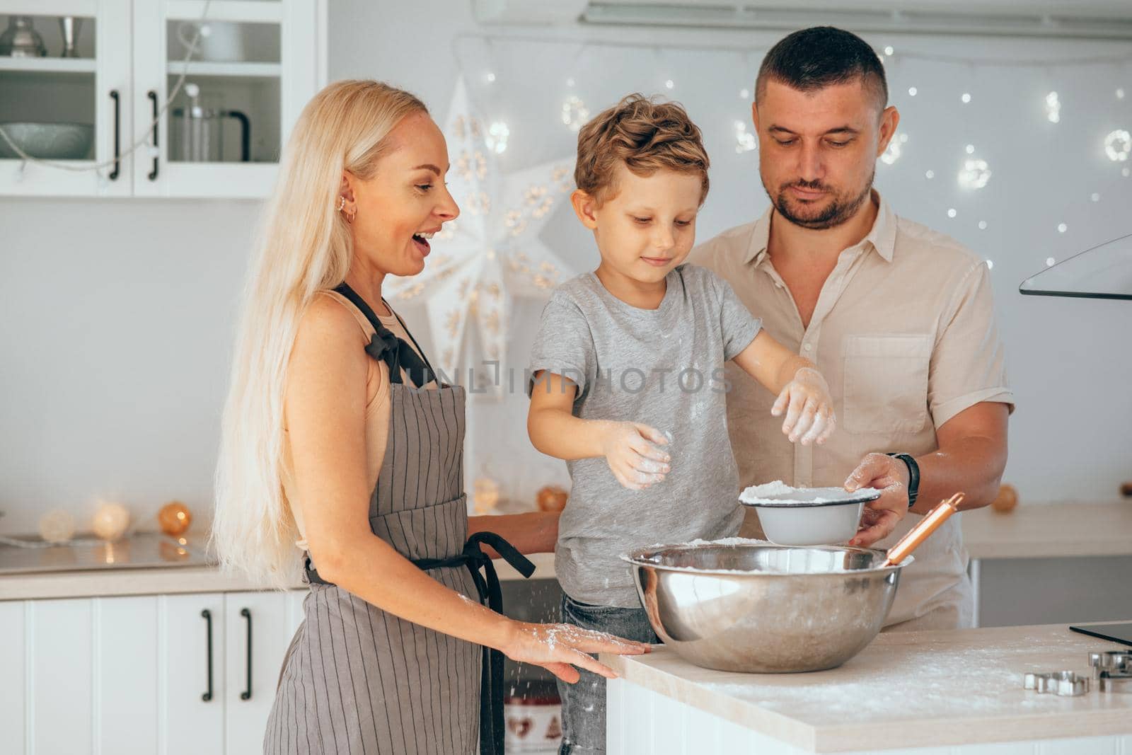 Happy family mother, father and son baking Christmas cookies on cozy kitchen. by XGroup