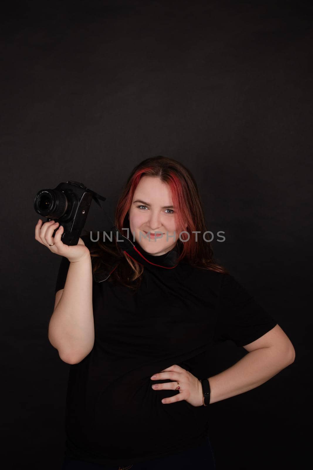 redhead girl with a professional camera posing on black background. woman female photographer. by oliavesna