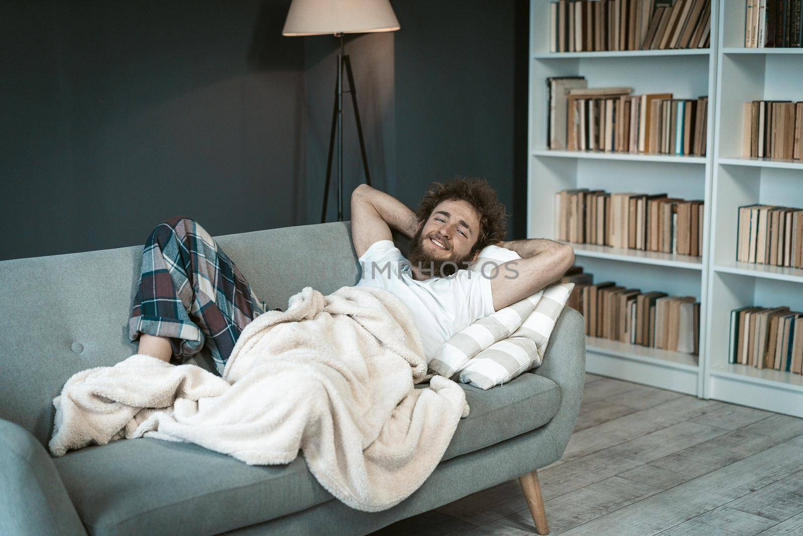 Young Man in Pajamas Enjoying Relaxing on the Couch. Cute Guy has a Rest on the Sofa in his Living Room at Home. Time to Sleep. Close-up. Copy Space. High quality photo