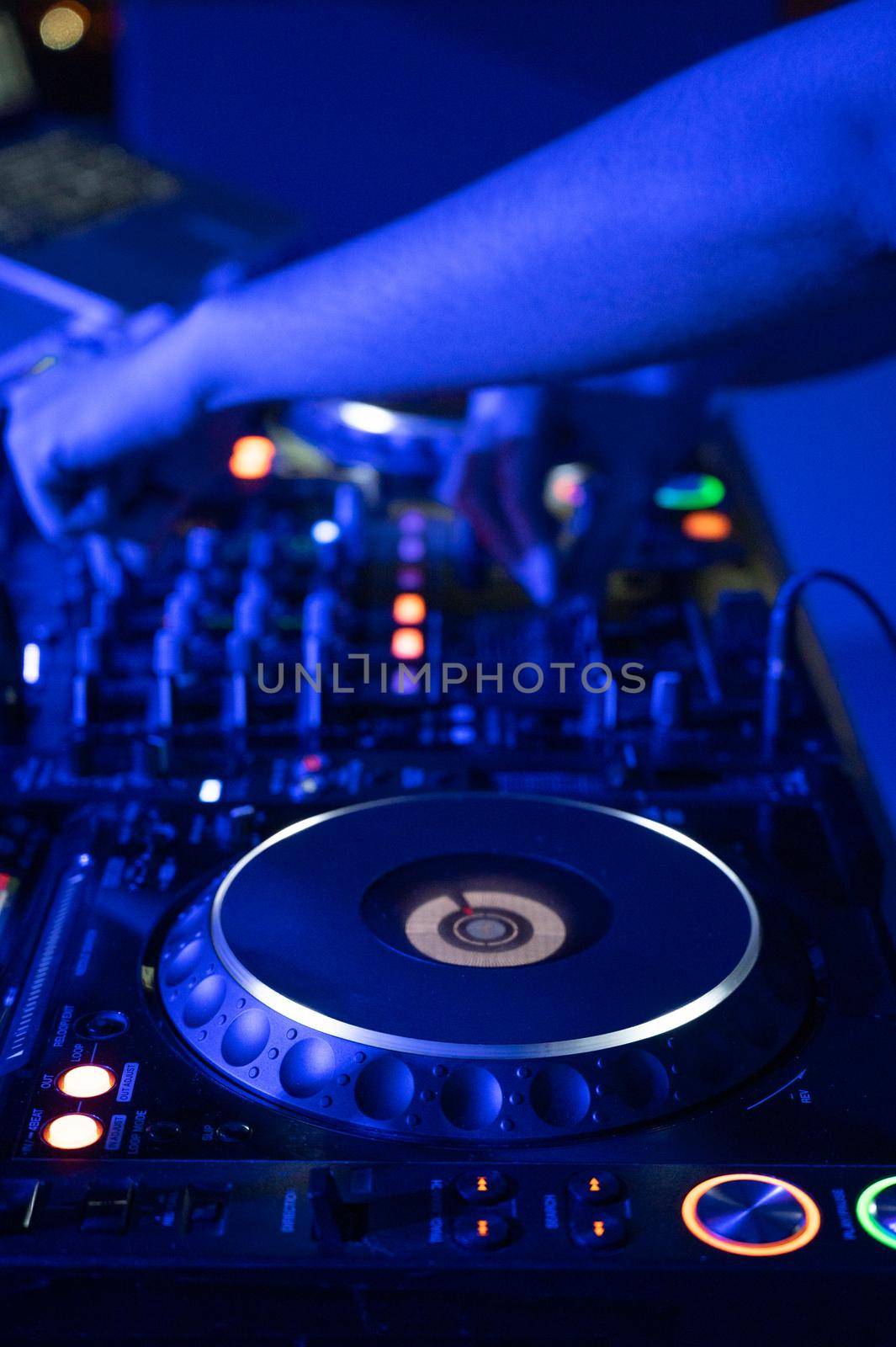 Close-Up of Dj Mixer Controller Desk in Night Club Disco Party. DJ Hands touching Buttons and Sliders Playing Electronic Music . by HERRAEZ