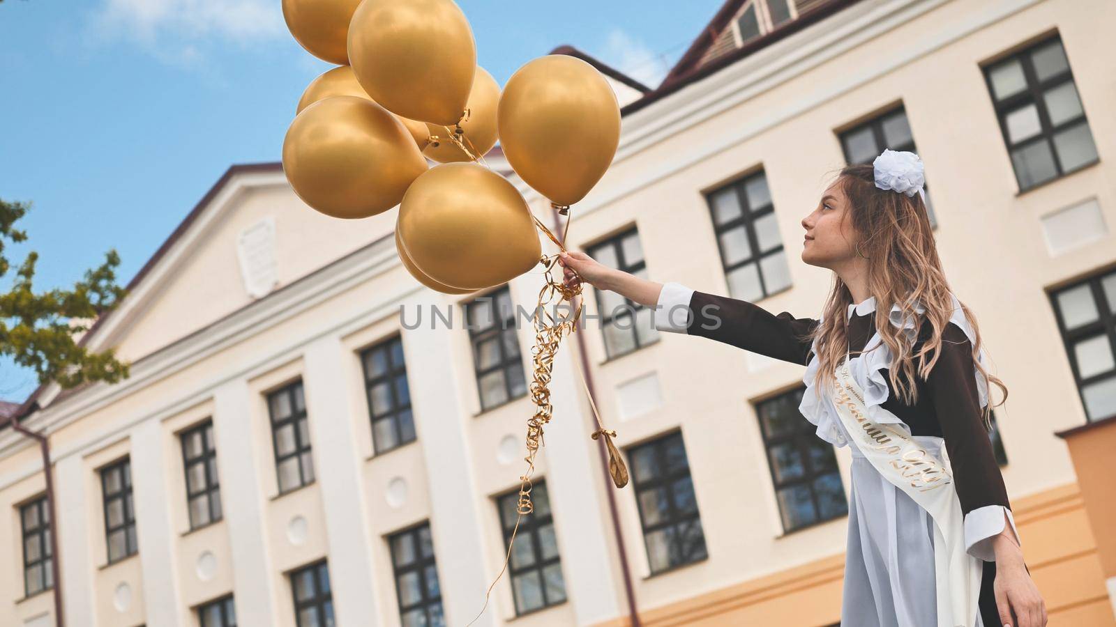 Happy Russian schoolgirl on the last day of school with balloons