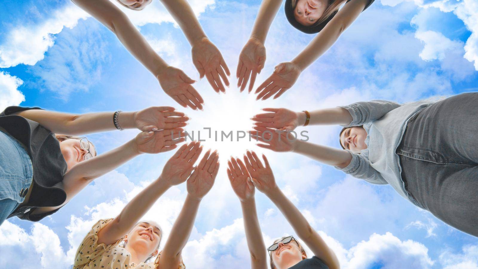 Joyful girls pull their palms to the center against the backdrop of a fabulous sky. by DovidPro