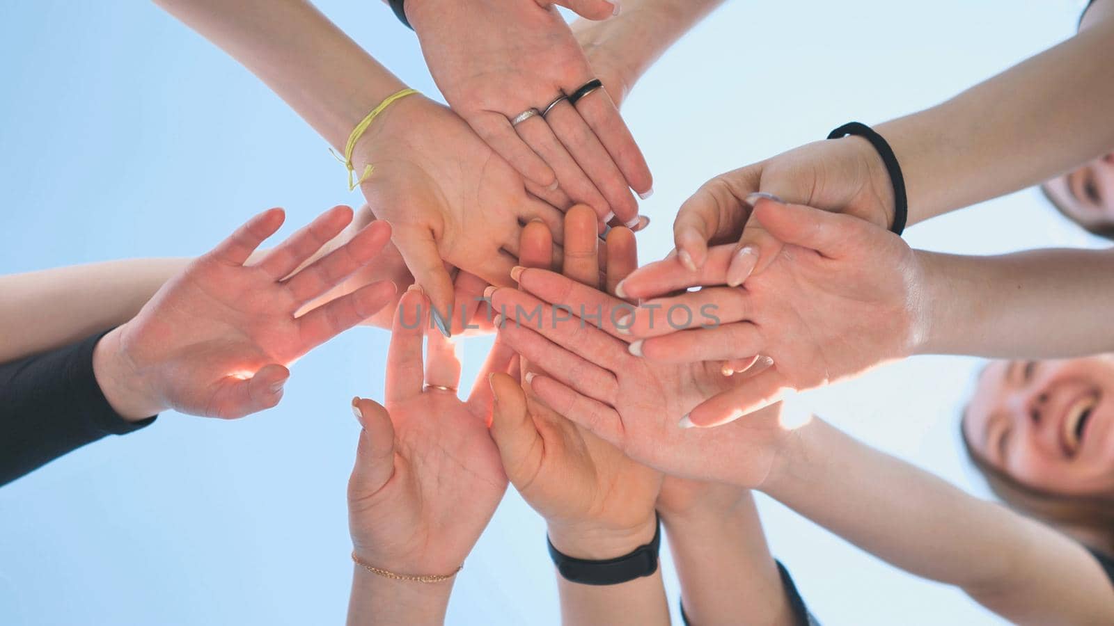 Cheerful girls join hands together as a sign of unity and joint successful work. Teamwork stacking hand concept