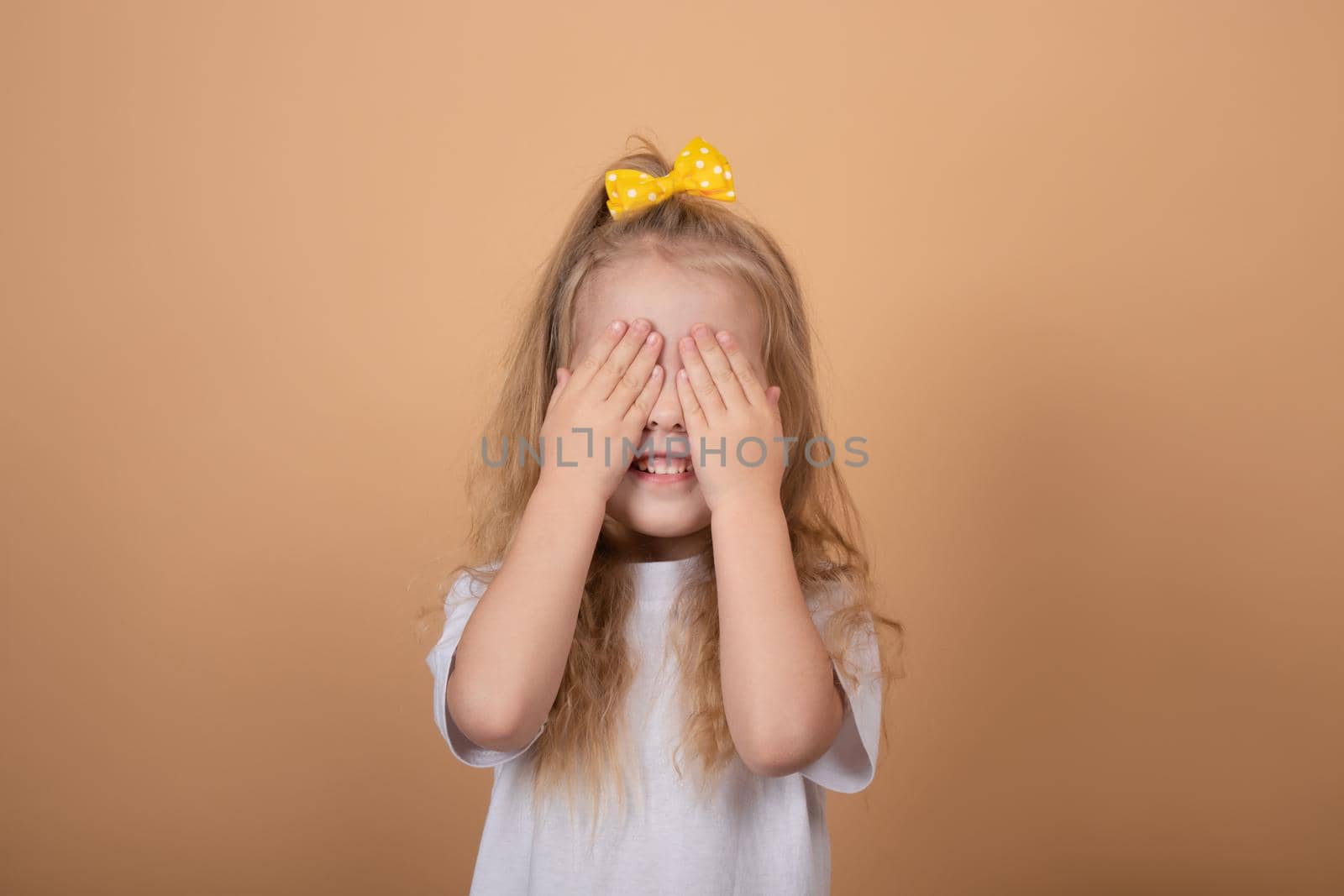 adorable blonde little girl in white t-shirt. on brown - yellow background. innocence child portrait.