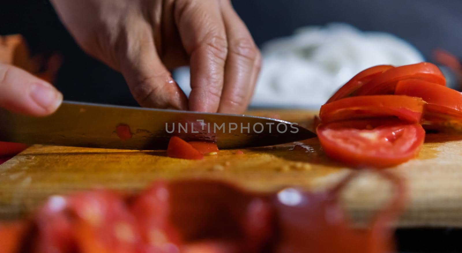 Hands slicing tomato on a wooden cutting board by Kanelbulle