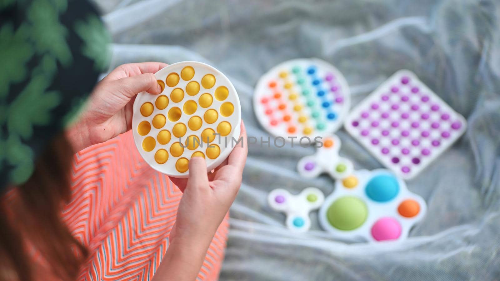 Teen girl plays with anti-stress toys popit and simple dimple in the park on a summer day