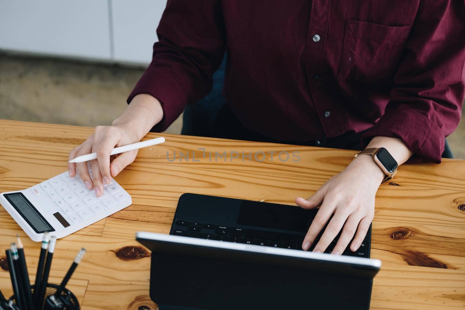 A female company employee is using a calculator to calculate sales income on a tablet computer screen via the Internet