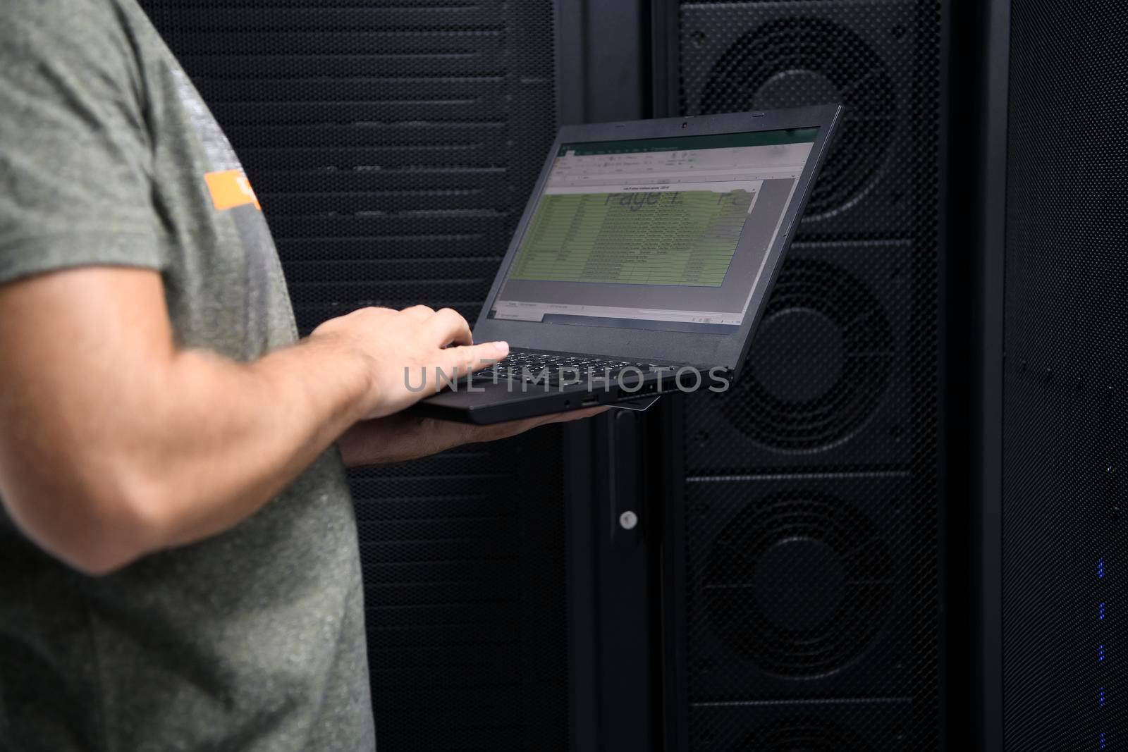 Data Center Engineer Using Laptop Computer Server Room Specialist Facility with Male System Administrator Working with Data Protection Network for Cyber Security or Cryptocurrency Mining Farm. by dotshock
