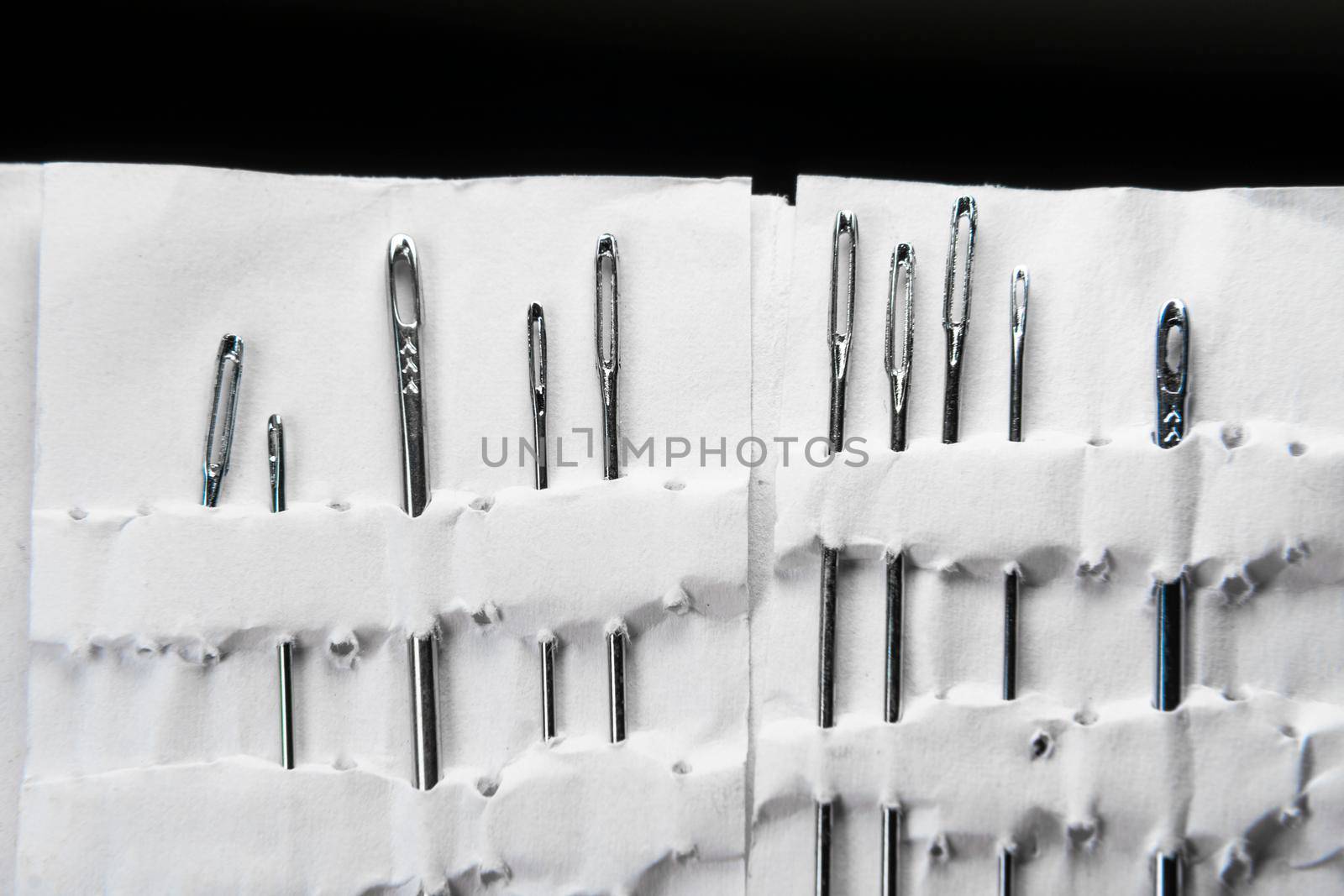 A set of sewing needles. Sewing and needlework classes.Workshop of hand craft and handmade.Workplace of the textile industry. Embroidery needles in a white package. Needle Factory