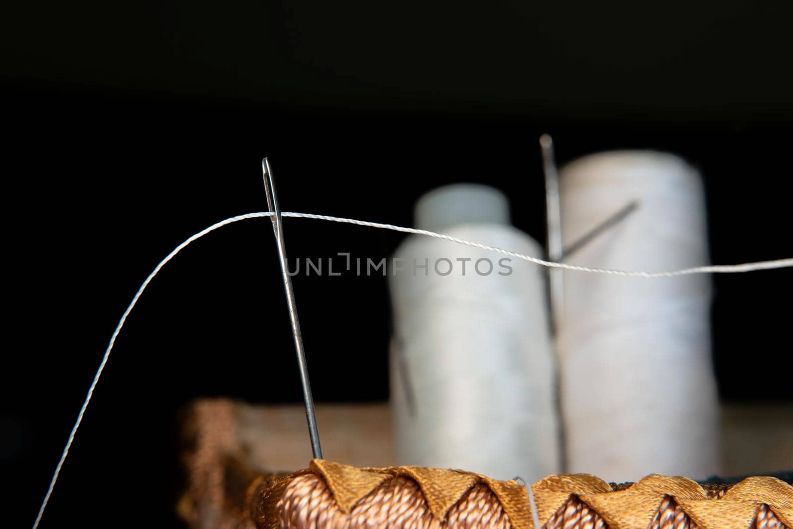 The thread is threaded through the eye of a sewing needle.Sewing and needlework classes.Workshop of hand craft and handmade.Workplace of the textile industry.The embroidery needle is stuck in a bobbin