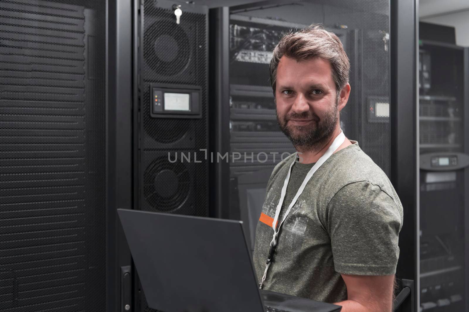 Data Center Engineer Using Laptop Computer Server Room Specialist Facility with Male System Administrator Working with Data Protection Network for Cyber Security or Cryptocurrency Mining Farm. by dotshock