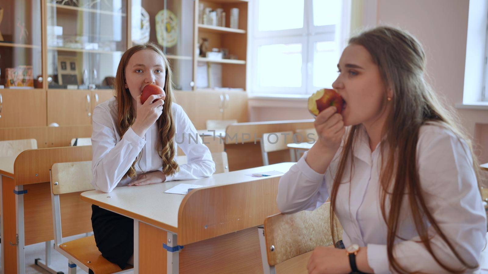 Girls eat apples in class during recess. by DovidPro