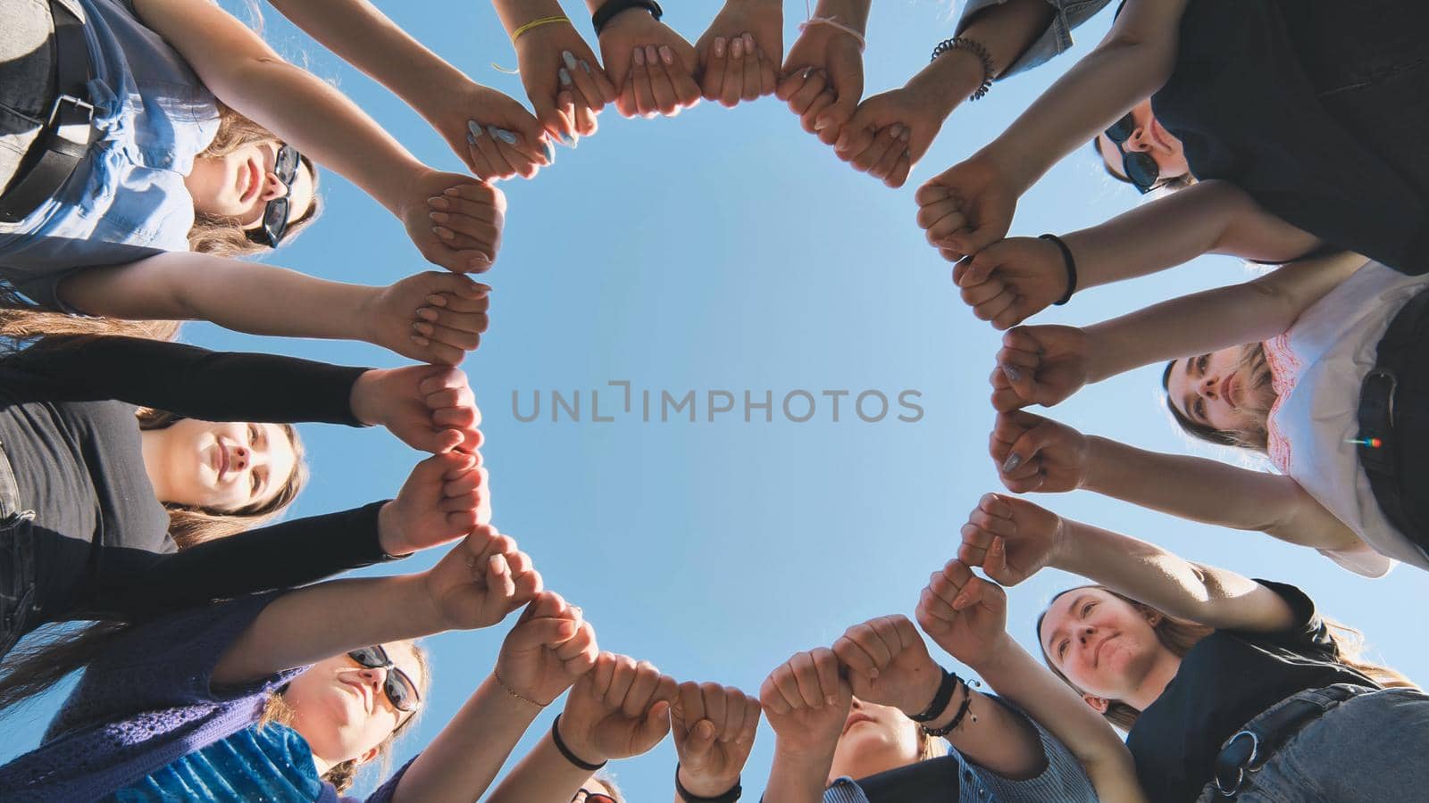 A group of girls makes a circle from their fists of their hands. by DovidPro