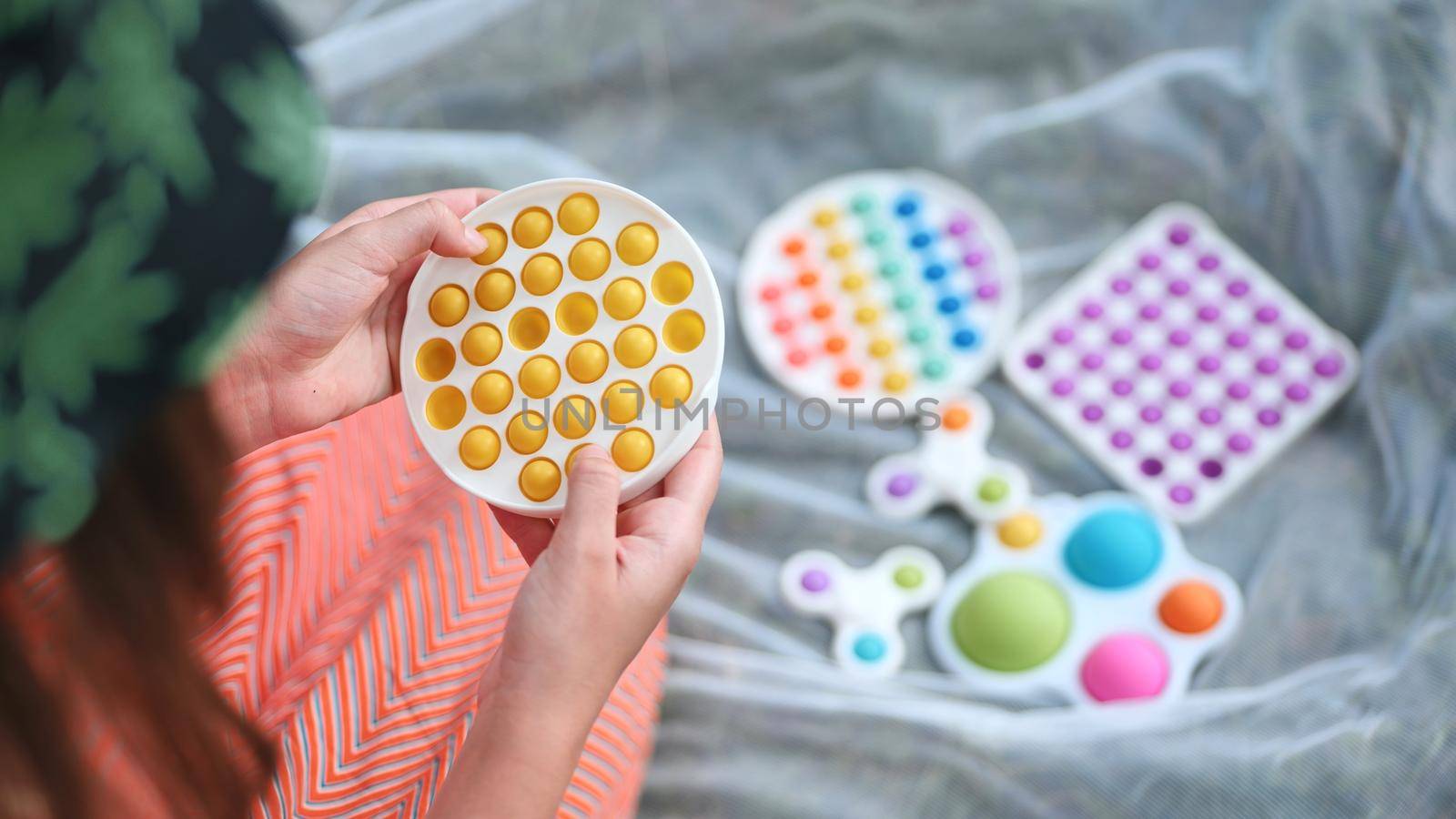 Teen girl plays with anti-stress toys popit and simple dimple in the park on a summer day