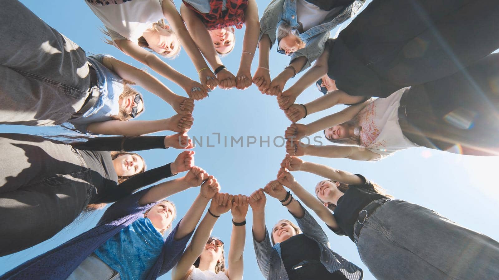 A group of girls makes a circle from their fists of their hands. by DovidPro