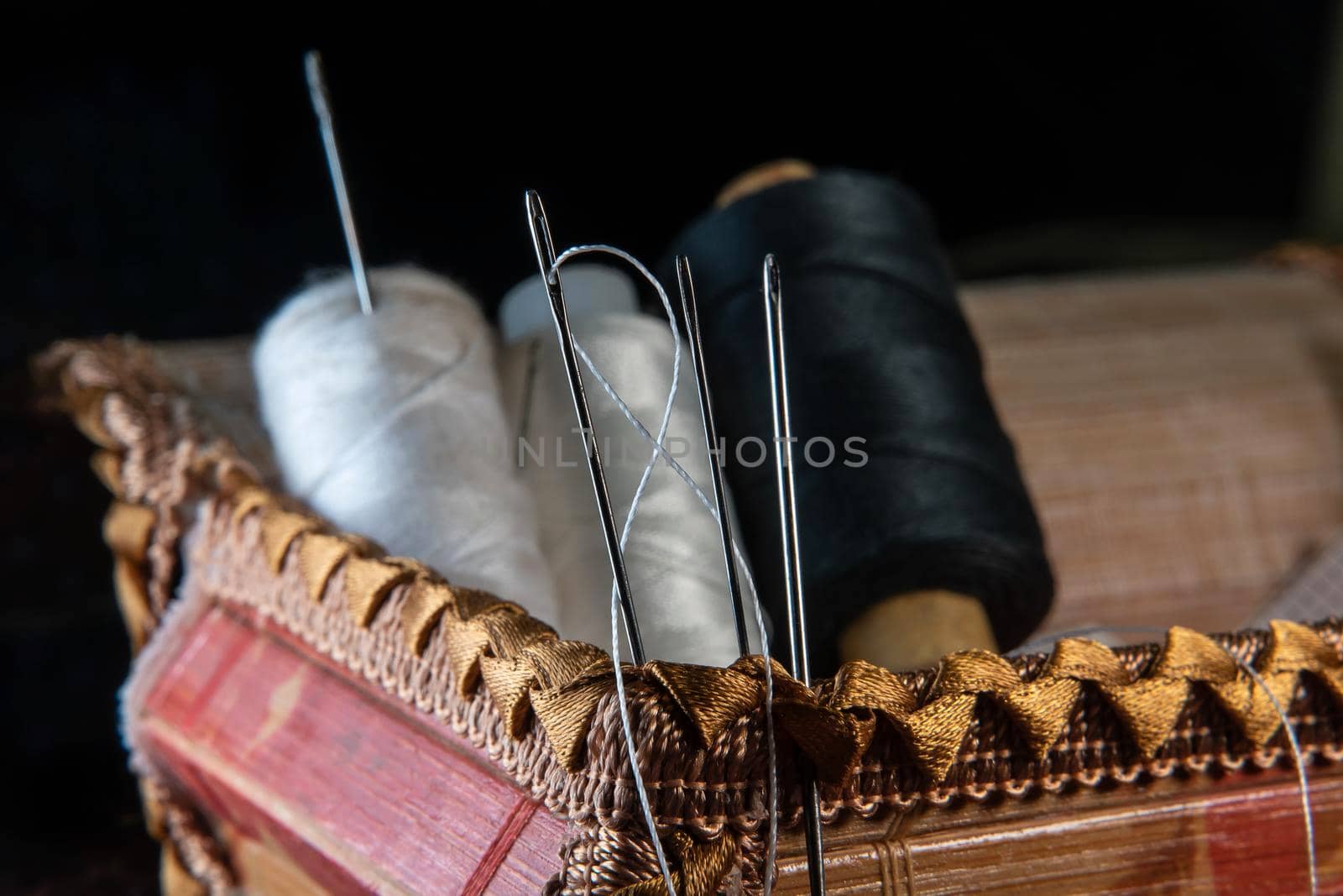 The thread is threaded through the eye of a sewing needle.Sewing and needlework classes.Workshop of hand craft and handmade.Workplace of the textile industry.The embroidery needle is stuck in a bobbin by YevgeniySam