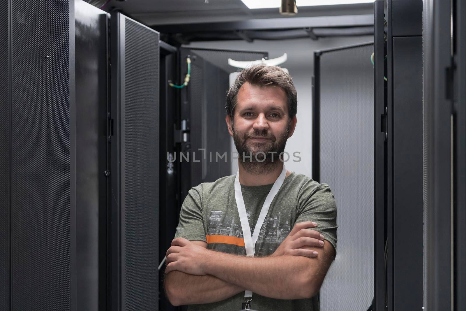 Portrait of male technician or network administrator standing brave as a hero with arms crossed in data center server room. by dotshock