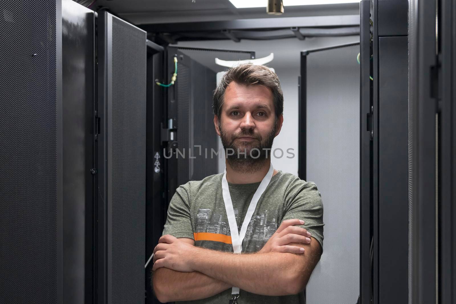 Portrait of male technician or network administrator standing brave as a hero with arms crossed in data center server room. by dotshock