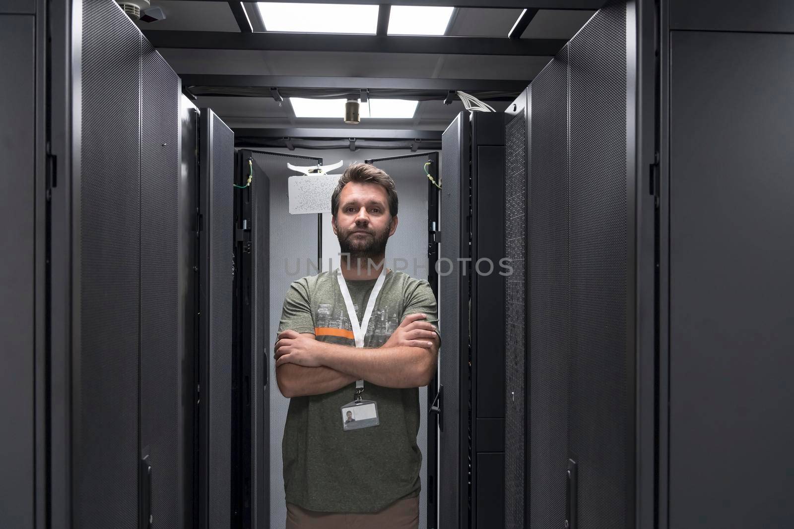 Portrait of male technician or network administrator standing brave as a hero with arms crossed in data center server room. by dotshock