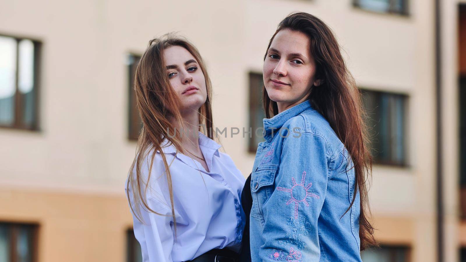 Two schoolgirls pose in front of their school