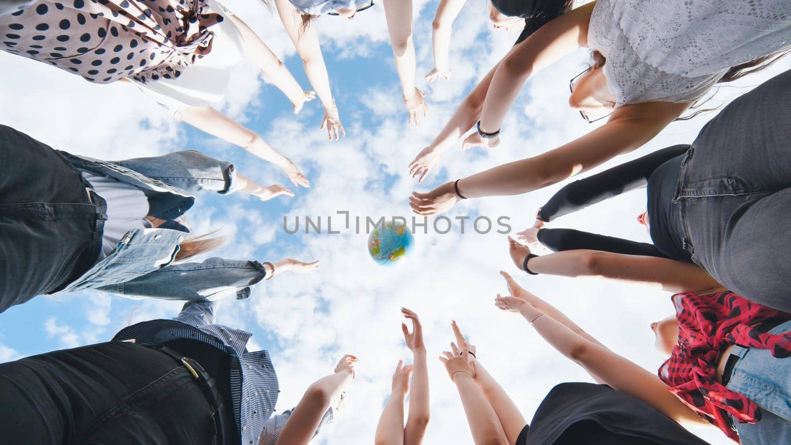 Female student girls standing in a circle toss the world globe up