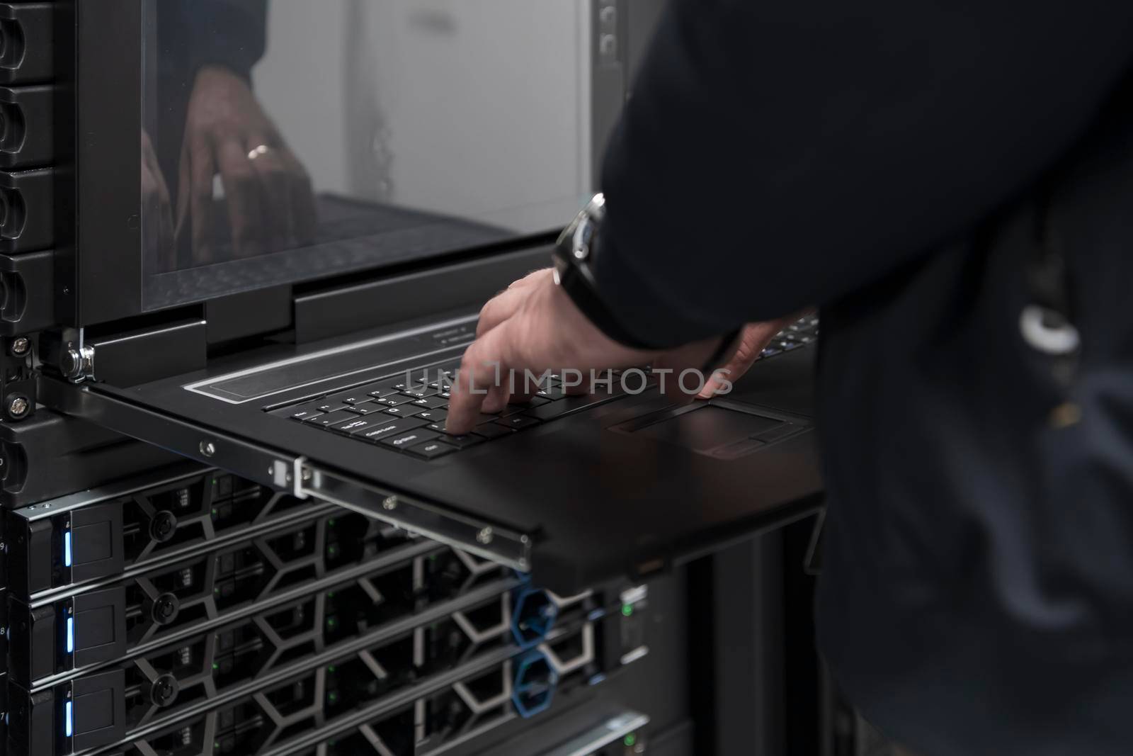Close up on Data Center Engineer hands Using keyboard on a supercomputer Server Room Specialist Facility with Male System Administrator Working with Data Protection Network for Cyber Security. by dotshock