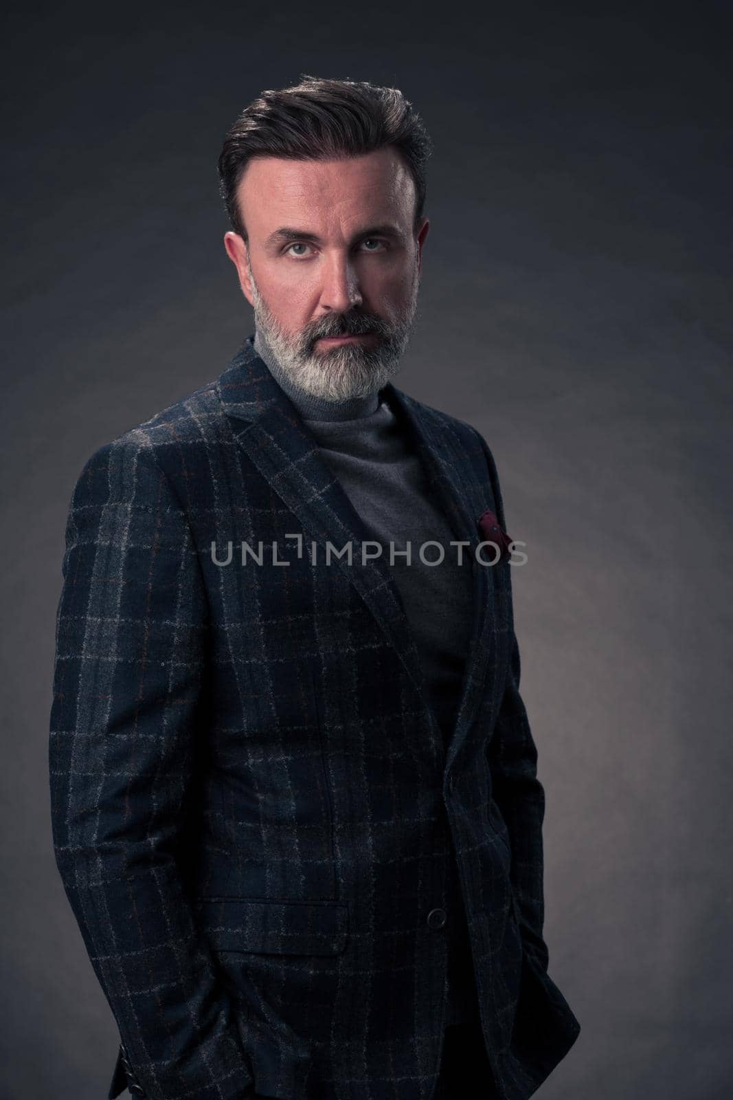 Portrait of a stylish elegant senior businessman with a beard and casual business clothes in photo studio isolated on dark background gesturing with hands by dotshock