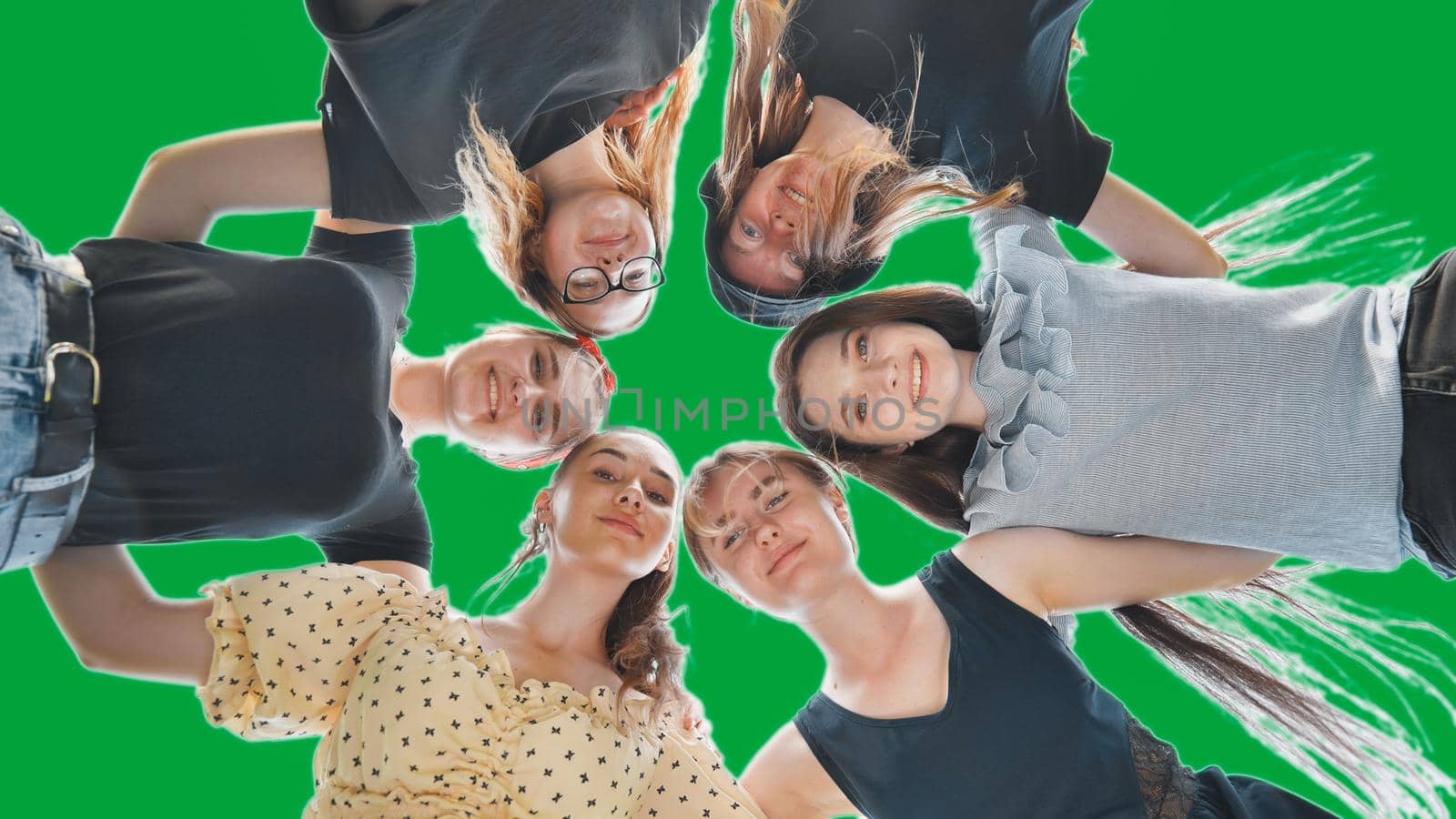 Happy girls friends hugging in a circle on a green background. by DovidPro