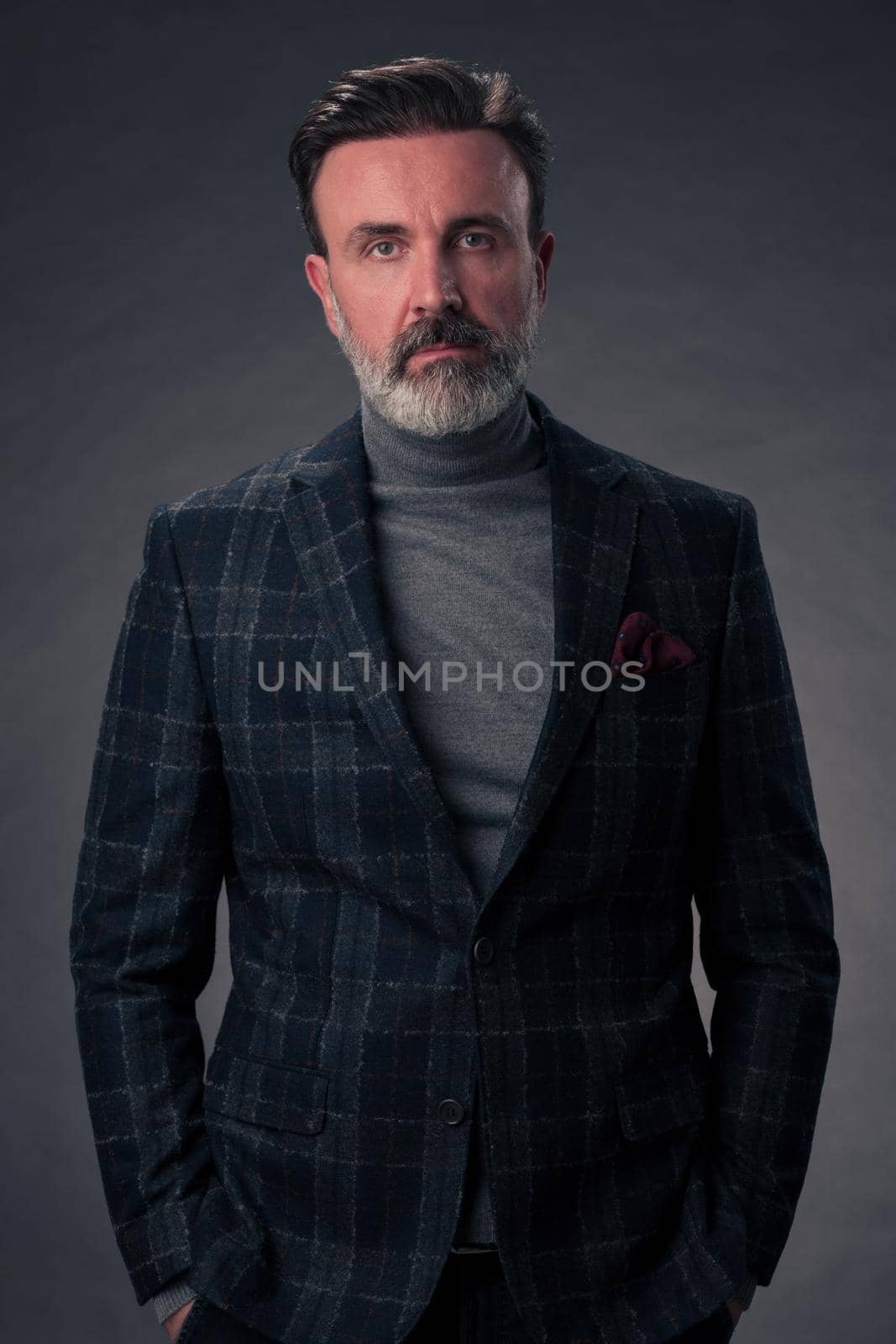 Portrait of a stylish elegant senior businessman with a beard and casual business clothes in photo studio isolated on dark background gesturing with hands by dotshock