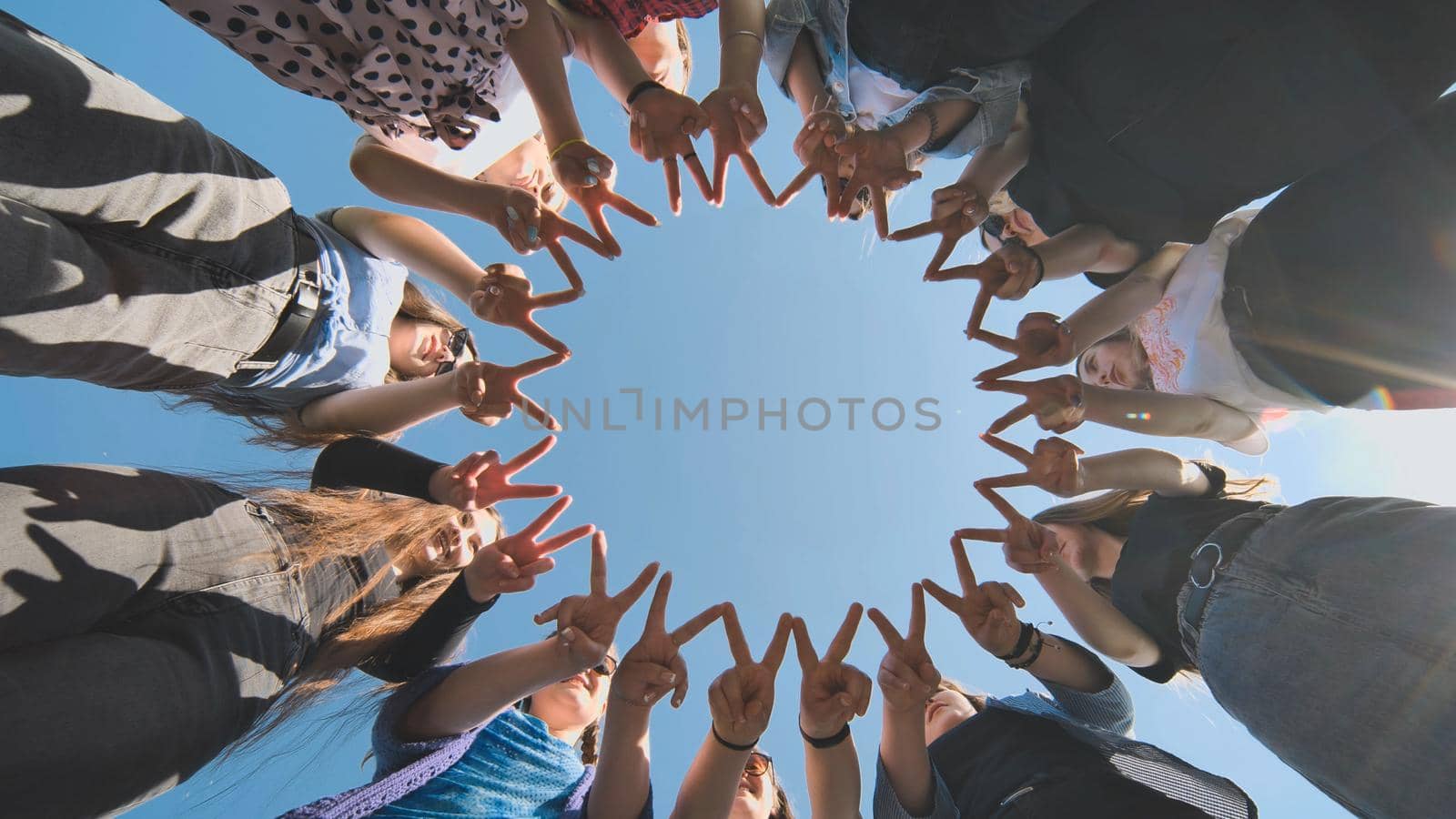 A group of girls makes a circle from their fingers. by DovidPro