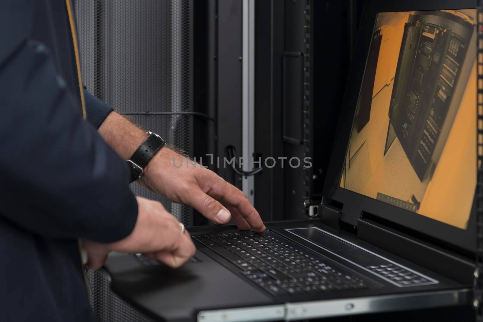 Close up on Data Center Engineer hands Using keyboard on a supercomputer Server Room Specialist Facility with Male System Administrator Working with Data Protection Network for Cyber Security. by dotshock