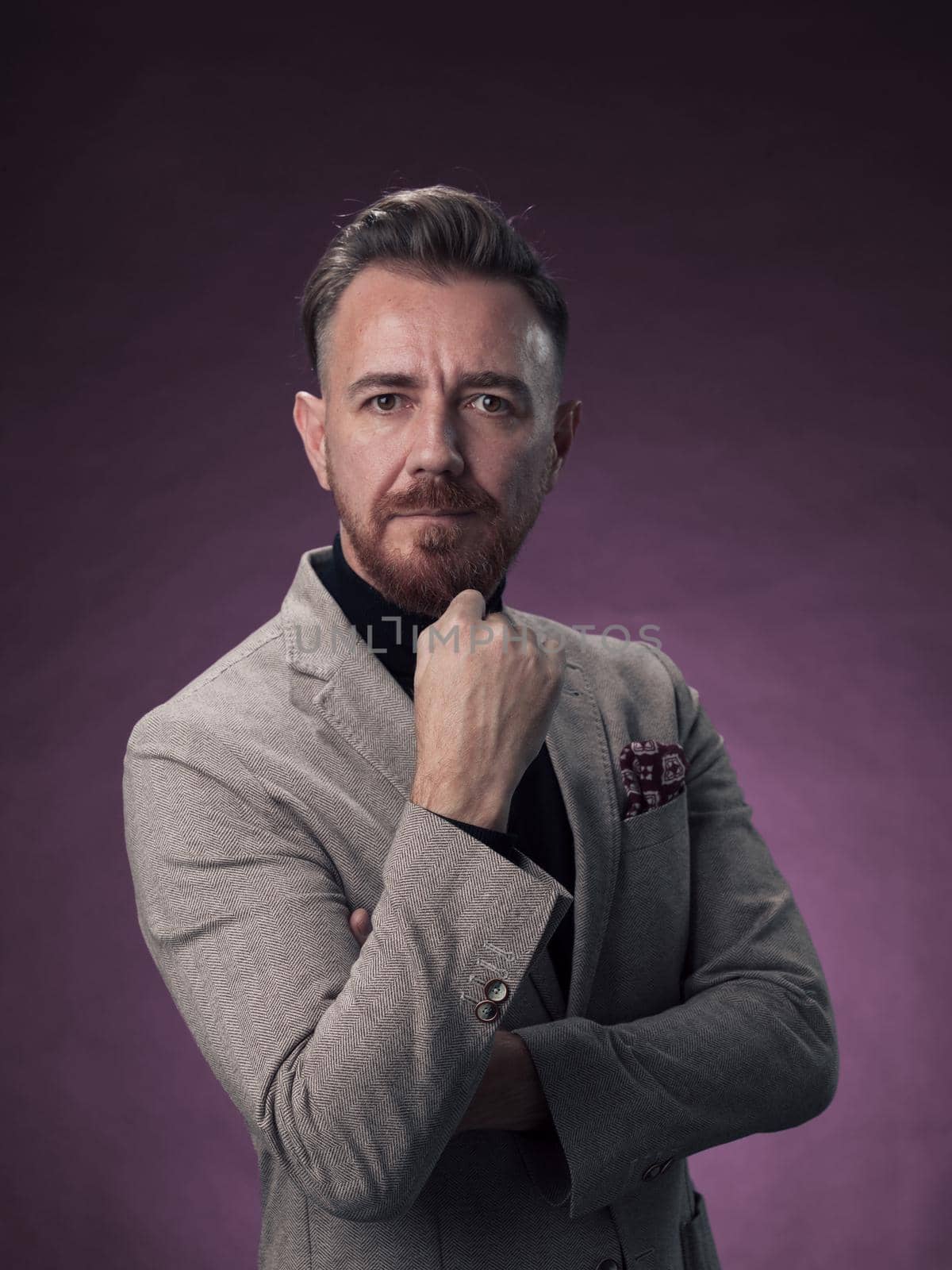 Portrait of a stylish elegant senior businessman with a beard and casual business clothes in photo studio isolated on dark background gesturing with hands. High quality photo