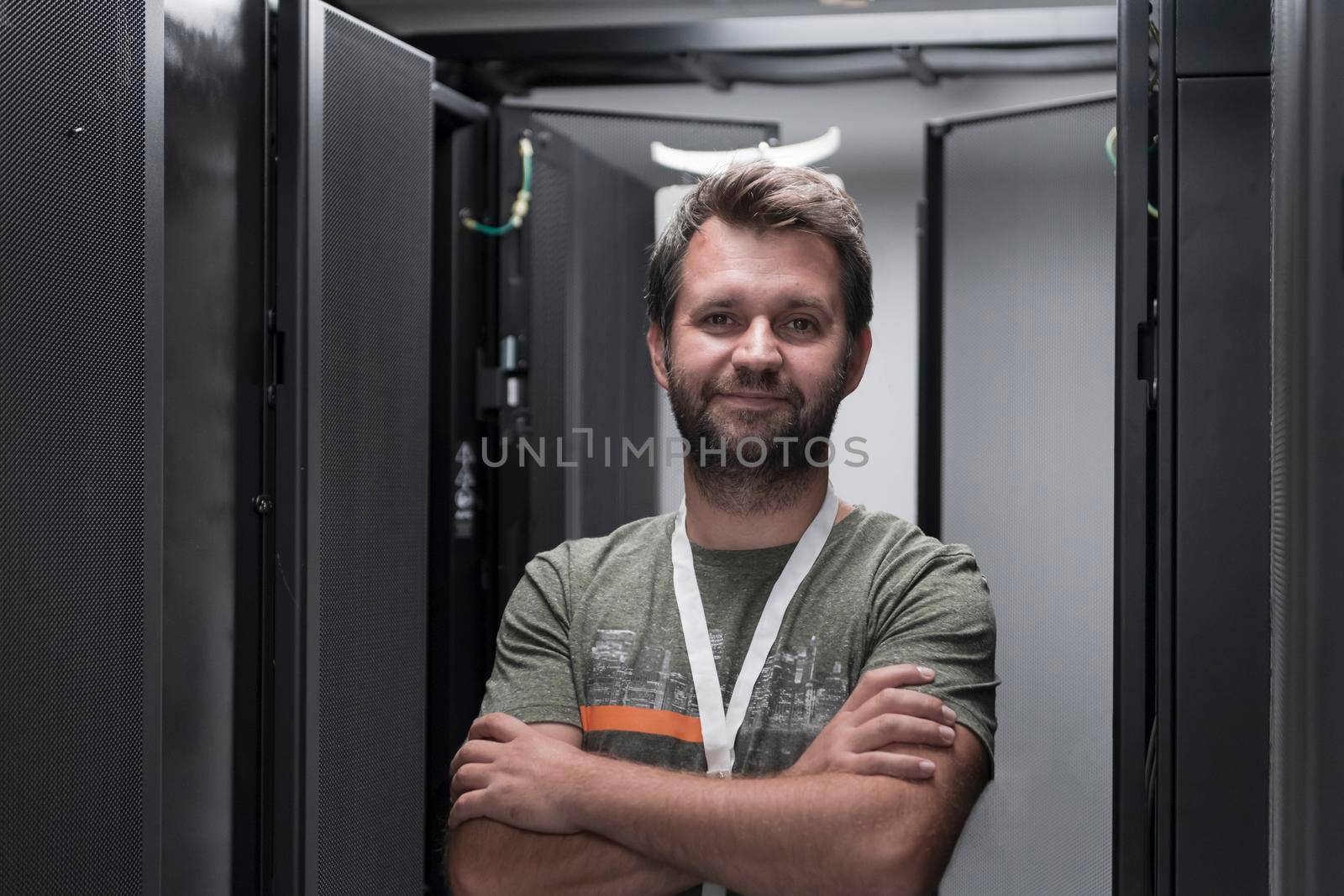 Portrait of male technician or network administrator standing brave as a hero with arms crossed in data center server room. by dotshock